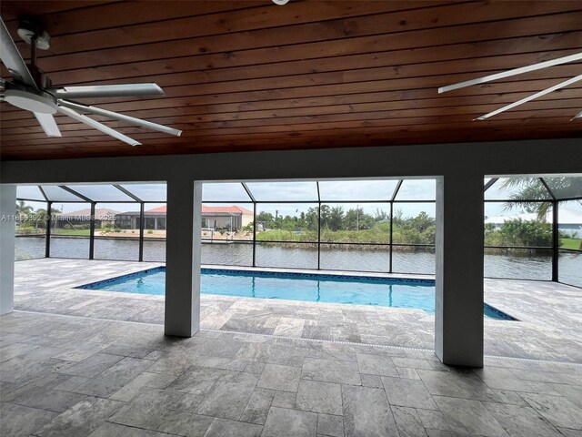 view of pool featuring a water view, a patio area, and a lanai