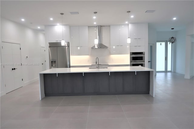 kitchen with white cabinetry, sink, built in refrigerator, wall chimney exhaust hood, and a spacious island