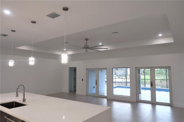 kitchen featuring french doors, sink, a raised ceiling, pendant lighting, and ceiling fan