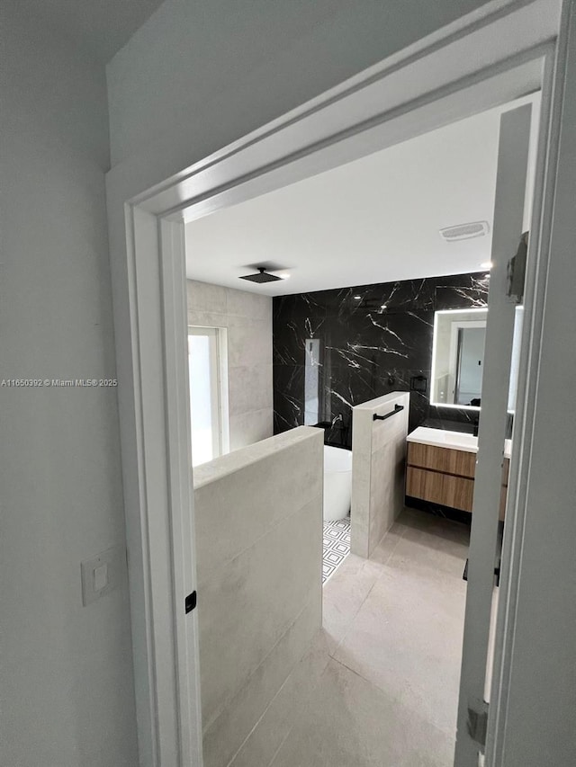 bathroom featuring tile walls, vanity, and walk in shower