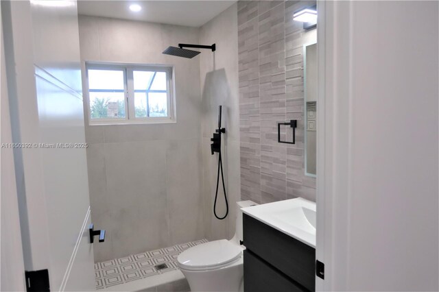 bathroom featuring vanity, tiled shower, tile walls, and toilet