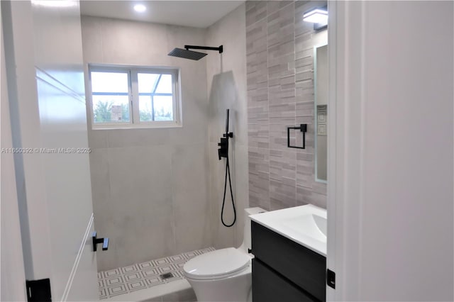 bathroom featuring vanity, toilet, and a tile shower