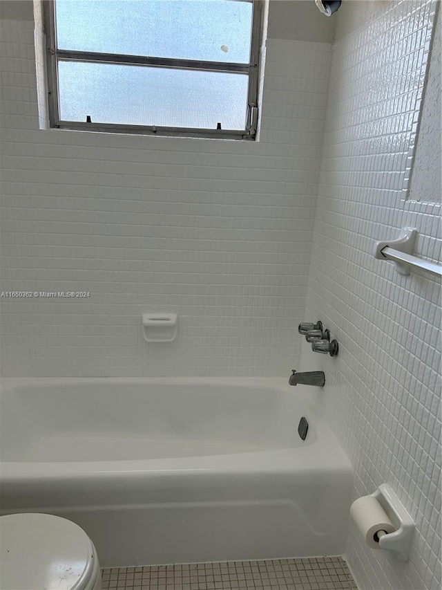 bathroom with tile patterned flooring, toilet, and tiled shower / bath