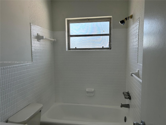 bathroom featuring tile walls, toilet, and tiled shower / bath combo