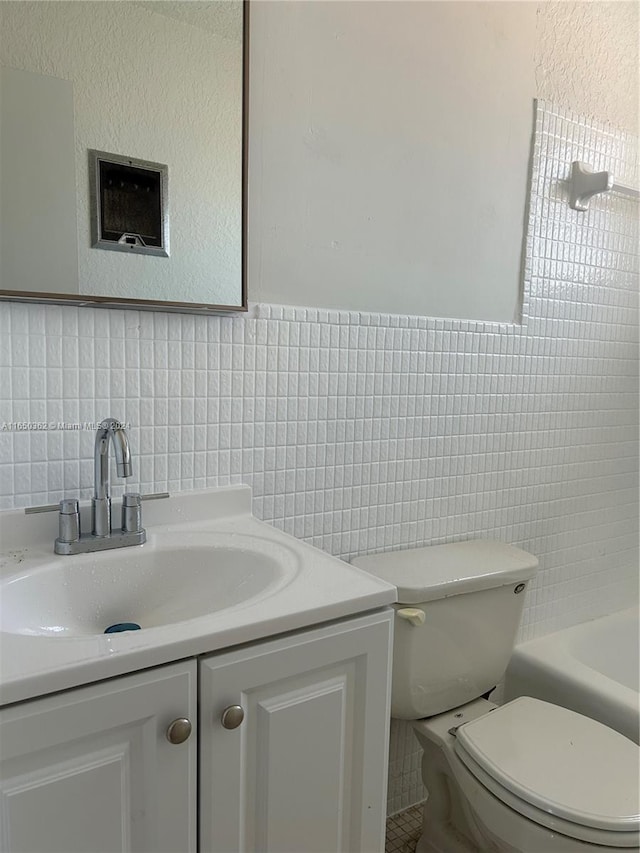 bathroom with vanity, toilet, tile walls, and decorative backsplash