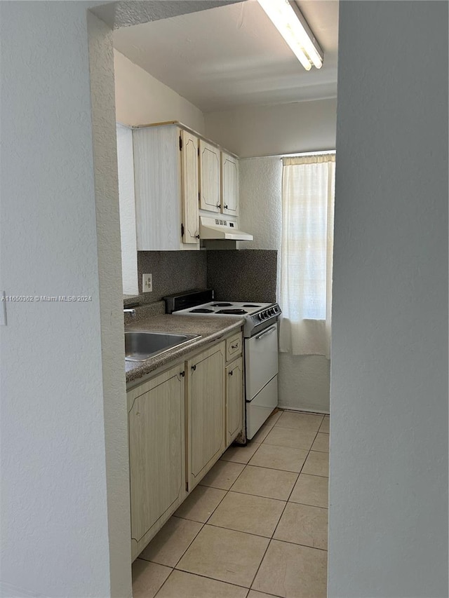 kitchen featuring light tile patterned floors, sink, and white range oven