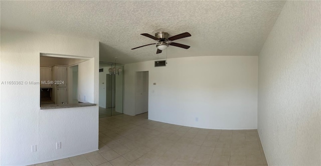 tiled empty room with ceiling fan with notable chandelier, vaulted ceiling, and a textured ceiling