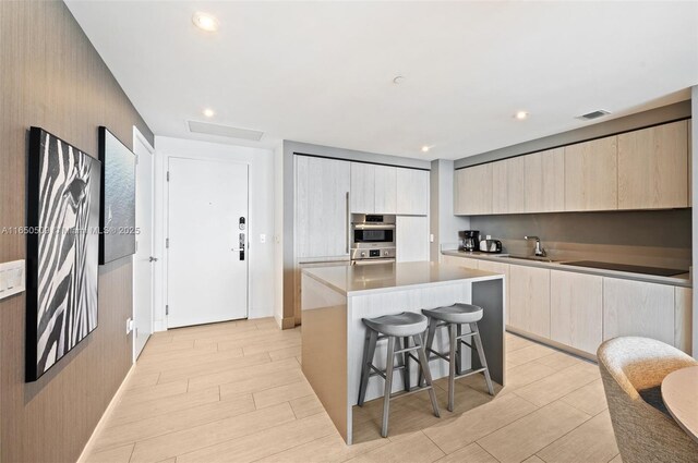 kitchen with sink, a breakfast bar, a center island, black electric cooktop, and stainless steel double oven