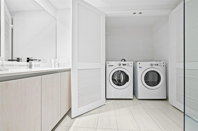 clothes washing area with light tile patterned flooring, sink, and washer and clothes dryer