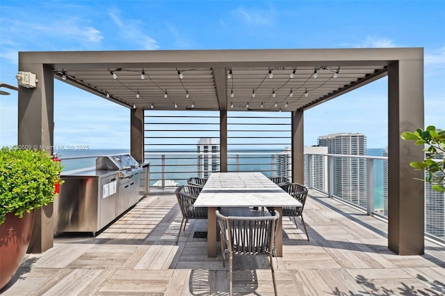 wooden terrace featuring a water view, a grill, and exterior kitchen