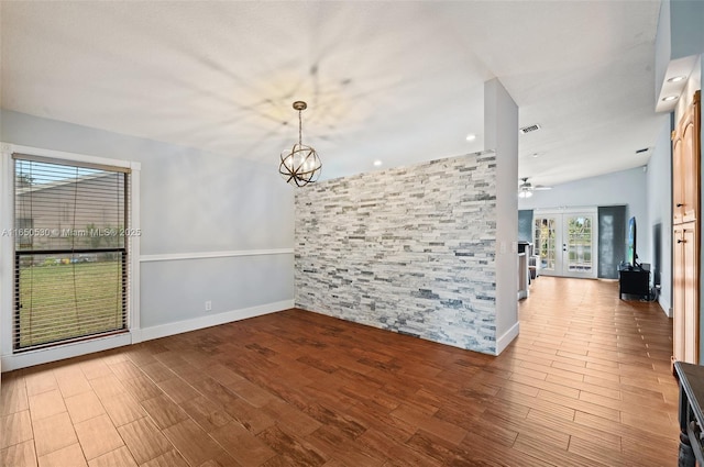 unfurnished room with lofted ceiling, french doors, and an inviting chandelier