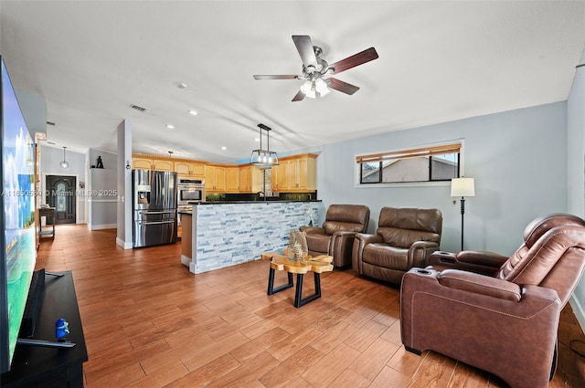 living room with light hardwood / wood-style floors, ceiling fan, and vaulted ceiling