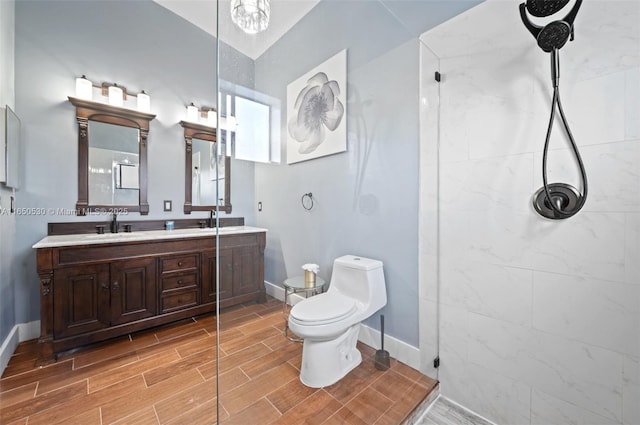 bathroom with toilet, tiled shower, and vanity