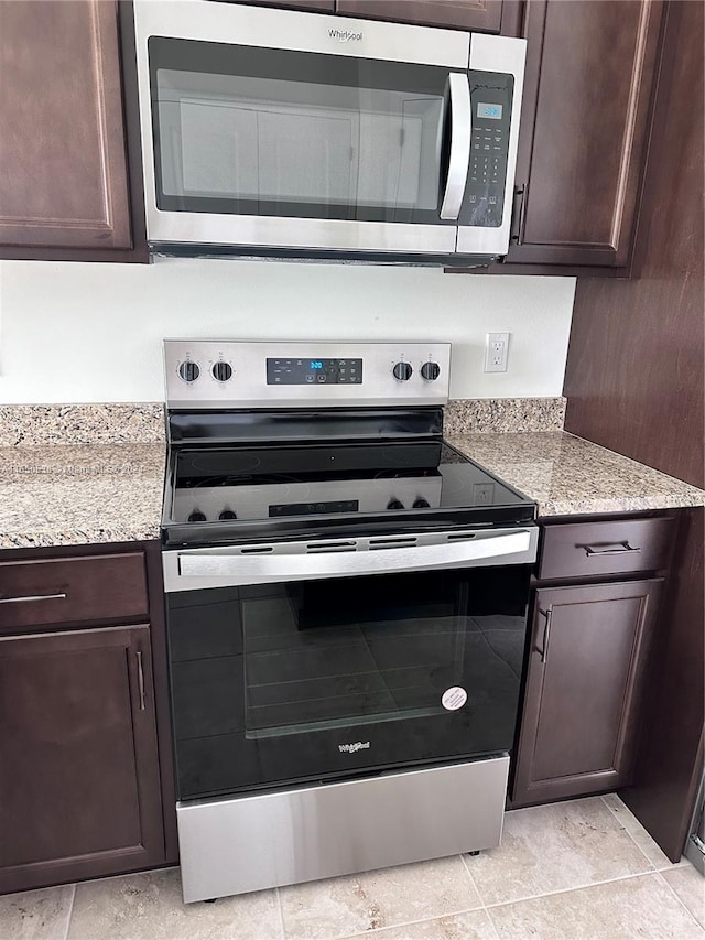 kitchen featuring appliances with stainless steel finishes, light stone counters, and dark brown cabinetry