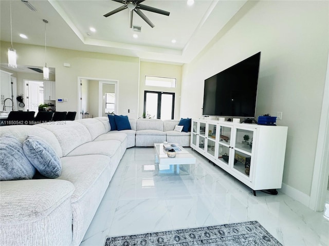 living room with ceiling fan, a raised ceiling, and french doors