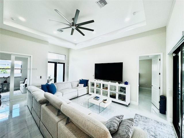 living room with a tray ceiling, ceiling fan, and french doors