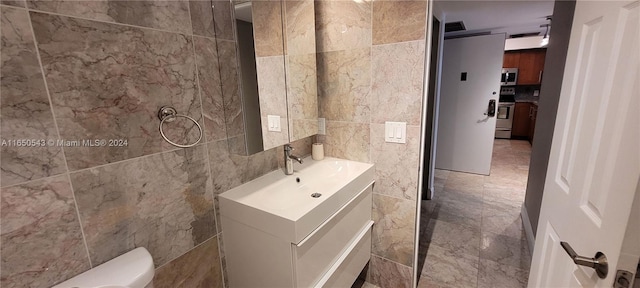 bathroom featuring tile walls, toilet, and vanity