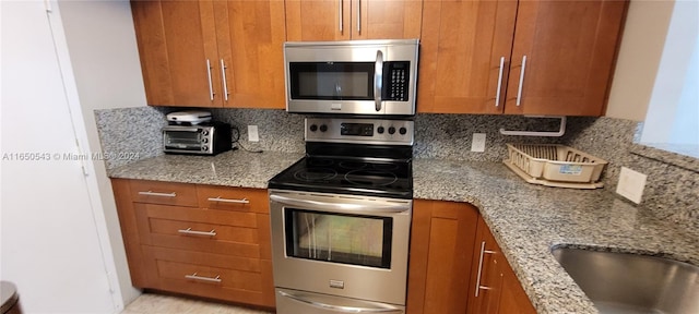 kitchen featuring light stone countertops, appliances with stainless steel finishes, and decorative backsplash