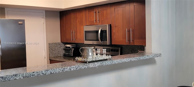 kitchen featuring stainless steel appliances, light stone counters, and tasteful backsplash