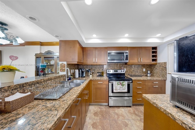 kitchen with tasteful backsplash, stainless steel appliances, kitchen peninsula, light stone counters, and sink