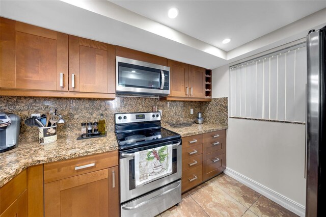 kitchen with appliances with stainless steel finishes, light stone counters, and backsplash