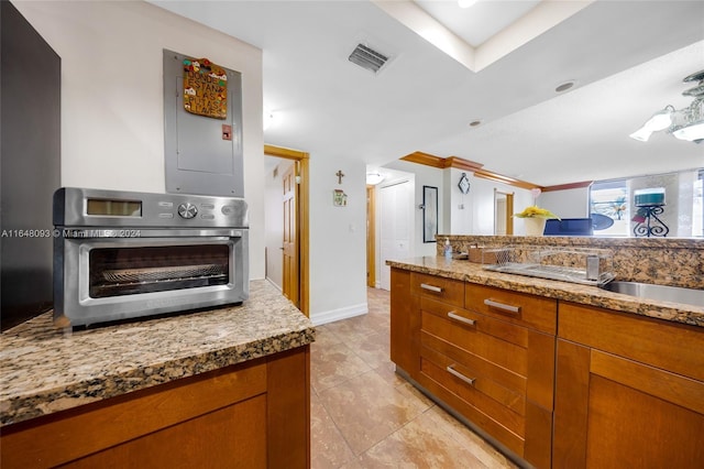 kitchen with visible vents, brown cabinetry, a sink, and stainless steel oven