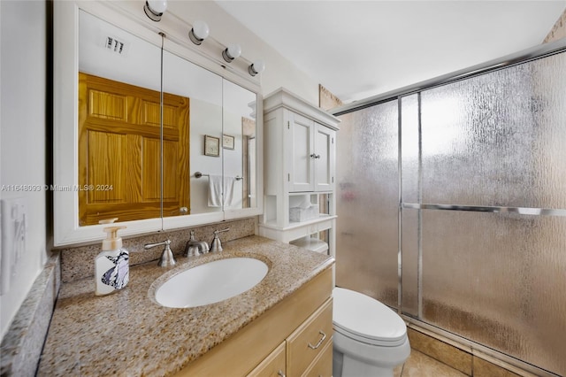 bathroom with vanity, toilet, an enclosed shower, and tile patterned flooring