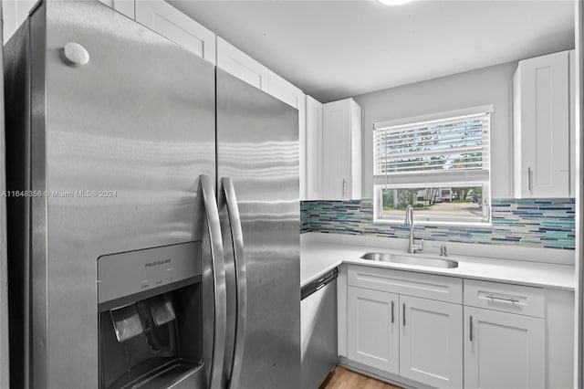 kitchen with white cabinets, tasteful backsplash, stainless steel appliances, and sink