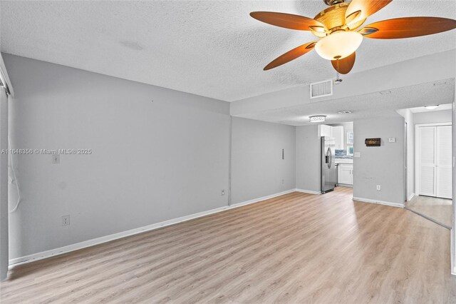 unfurnished living room with a textured ceiling, ceiling fan, and light wood-type flooring