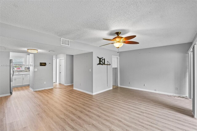 interior space featuring a textured ceiling, light hardwood / wood-style flooring, and ceiling fan