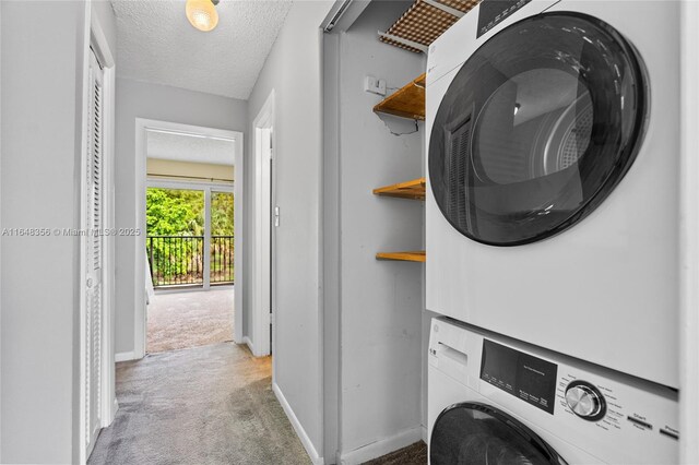 laundry area featuring stacked washer and dryer, a textured ceiling, and light colored carpet