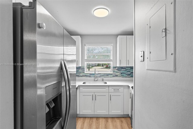 kitchen with white cabinets, light wood-type flooring, electric panel, stainless steel appliances, and ceiling fan