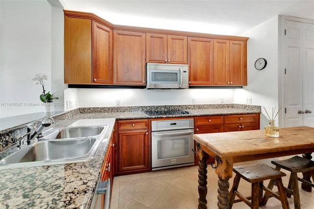 kitchen with light stone counters, sink, light tile patterned flooring, and appliances with stainless steel finishes