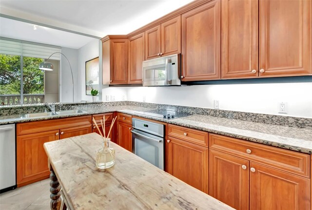 kitchen featuring light stone counters, sink, light tile patterned floors, and stainless steel appliances