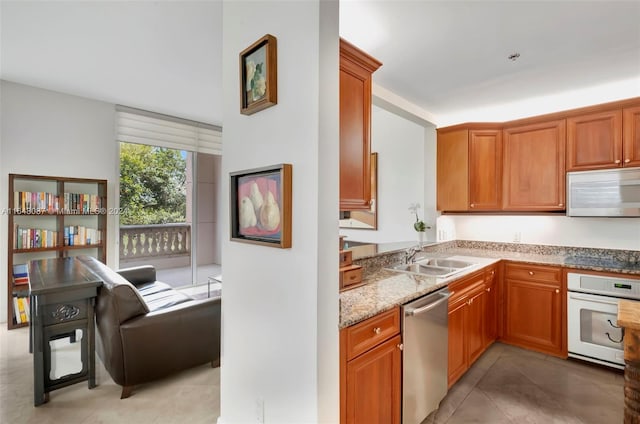 kitchen featuring light stone countertops, light tile patterned floors, white appliances, and sink