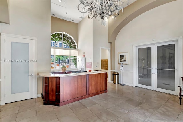 bar featuring light tile patterned flooring, a high ceiling, and an inviting chandelier