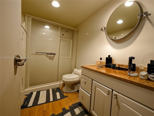 bathroom with vanity, toilet, wood-type flooring, and a shower with shower door