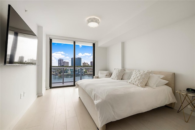 bedroom with light wood-type flooring, floor to ceiling windows, and access to exterior