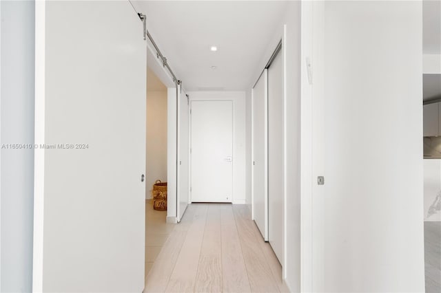 hallway with a barn door and light hardwood / wood-style floors