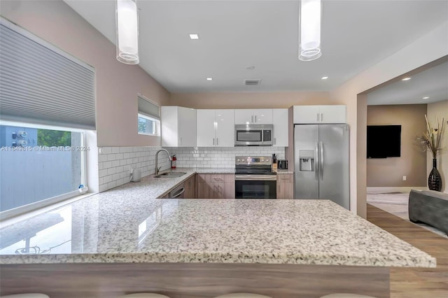 kitchen with white cabinets, backsplash, stainless steel appliances, sink, and wood-type flooring