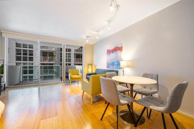 dining area with light hardwood / wood-style flooring and rail lighting