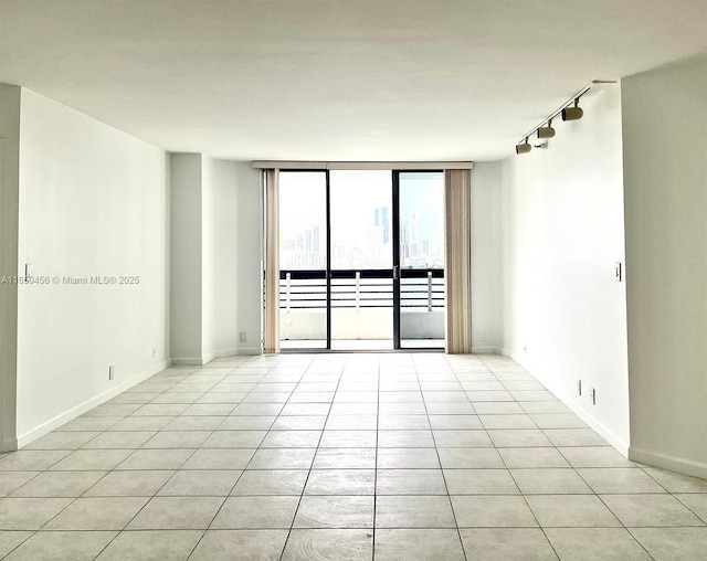 tiled spare room featuring expansive windows and rail lighting