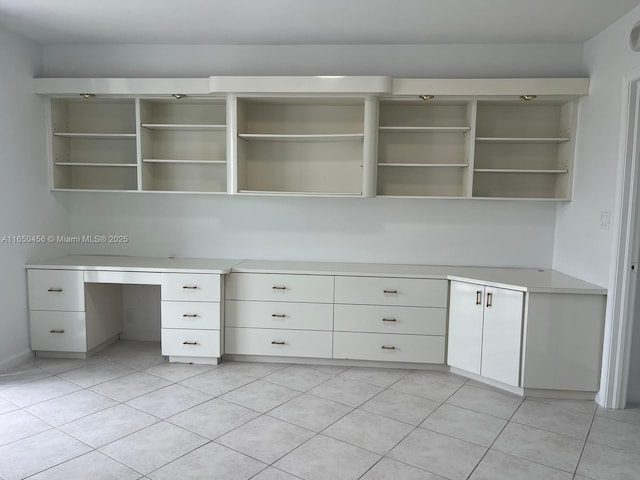 unfurnished office featuring light tile patterned floors and built in desk