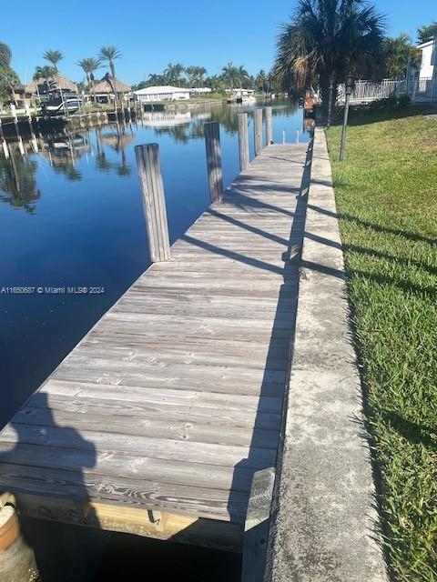 dock area with a water view and a lawn