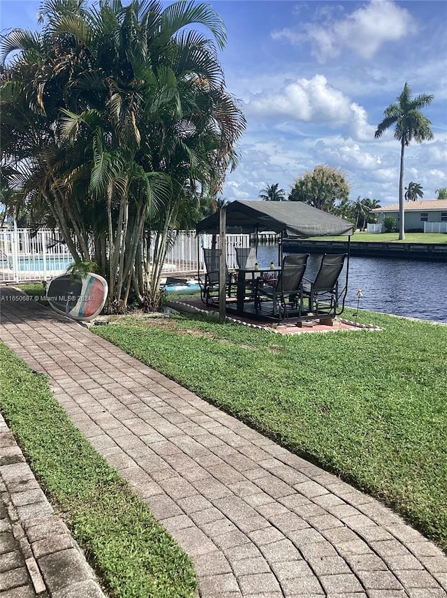 dock area featuring a water view, a yard, a patio, and a gazebo