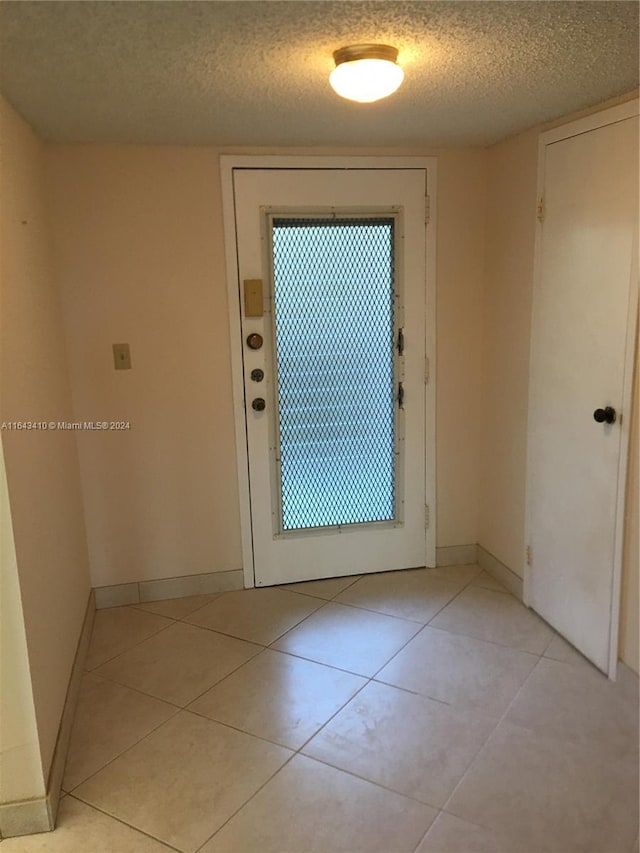 entryway with a textured ceiling and light tile patterned floors