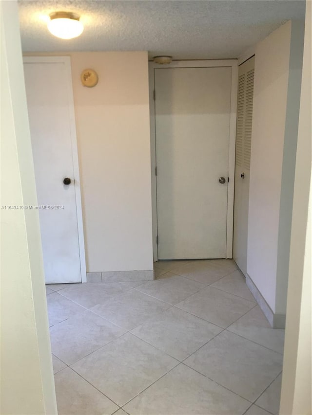 hall featuring light tile patterned floors and a textured ceiling