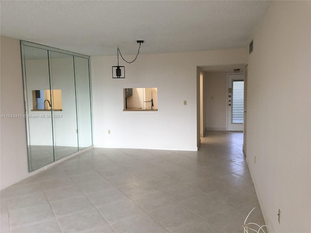 interior space featuring a textured ceiling, a closet, light tile patterned floors, and white refrigerator