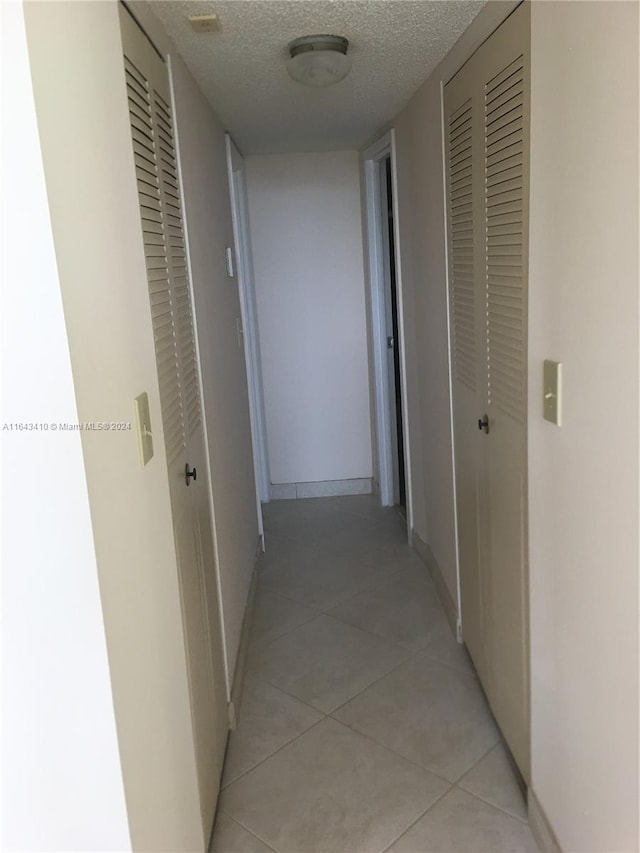 hallway with light tile patterned flooring and a textured ceiling