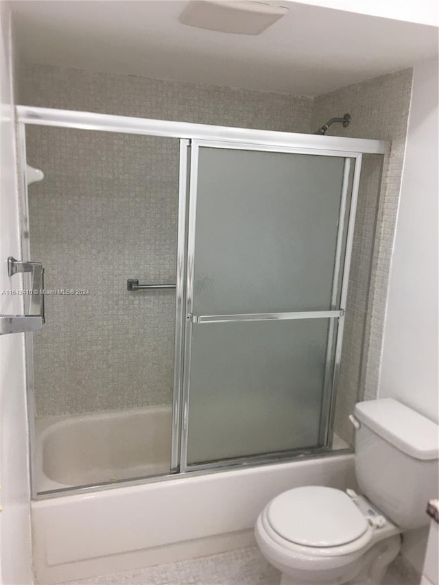 bathroom featuring shower / bath combination with glass door and toilet